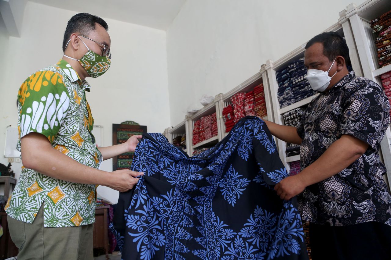 Aryono mendiskusikan kain yang hendak dijadikan pakaian sesuai dengan pesanan.