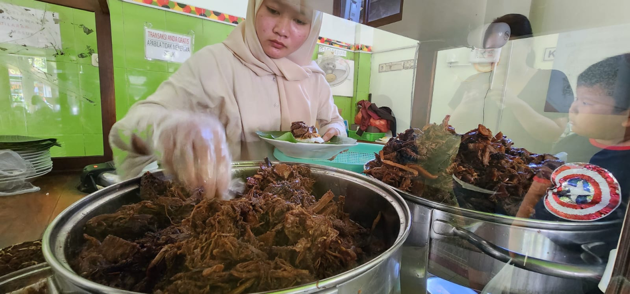 Karyawan sedang menyajikan porsi Nasi Krawu Bu Azza Gresik. Foto : Peni Widarti