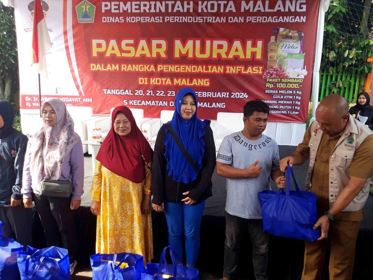 Kepala Dinas Koperasi, Perindustrian dan Perdagangan Kota Malang Eko Sri Yuliadi (kanan) menyerahkan paket bahan pangan ke warga dalam pasar murah di Kelurahan Merjosari, Selasa (20/2). Pasar murah merambah lima kecamatan menjual 9.500 paket bahan pangan 