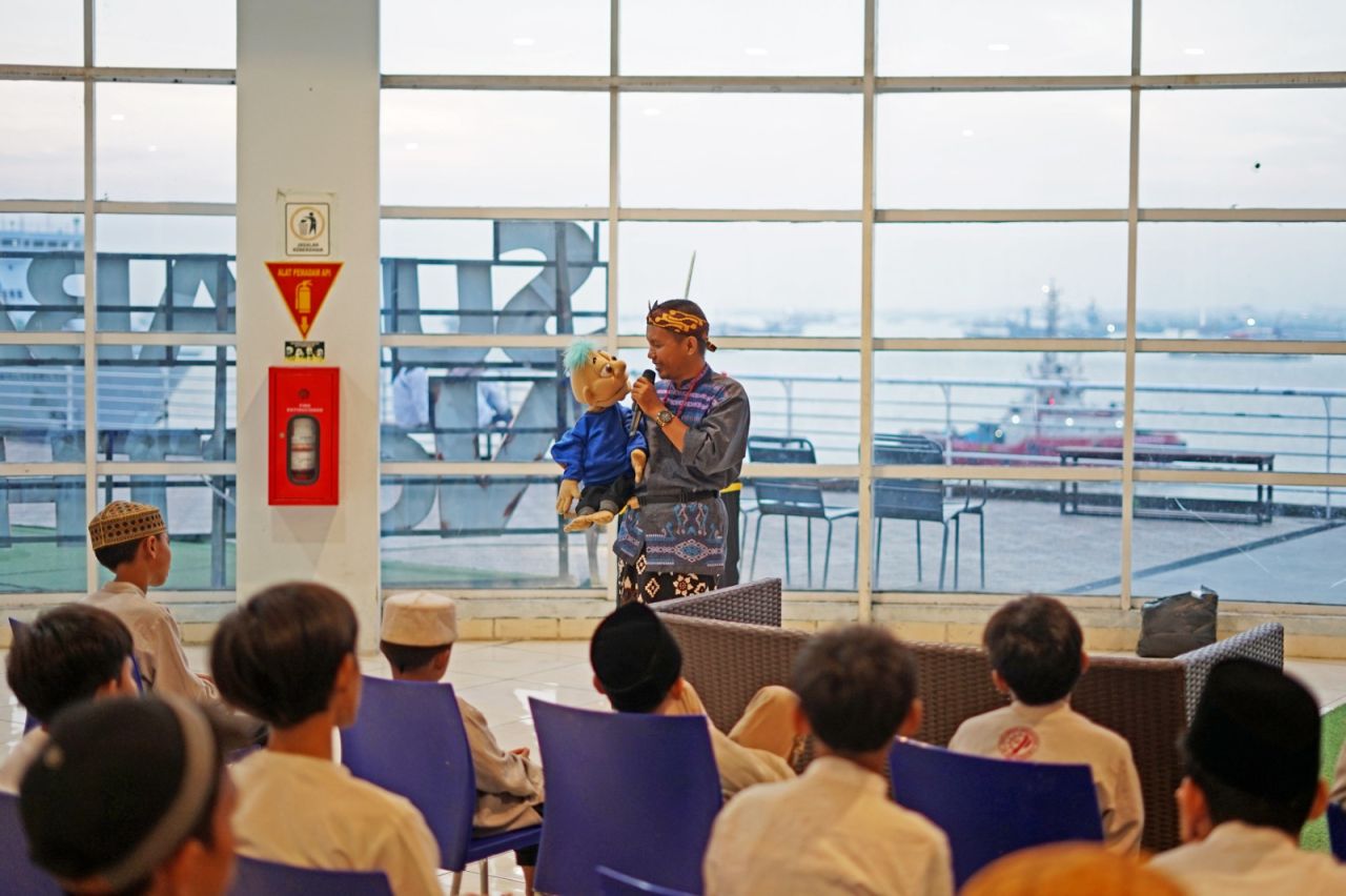 Pencerita boneka ventriloquist, Trianto, mengisahkan peringatan Nuzulul Quran kepada anak-anak yatim piatu dalam ngabuburit maritim di Surabaya North Quay, Senin (25/3/2024). (Foto: dok.Pelindo Marine)