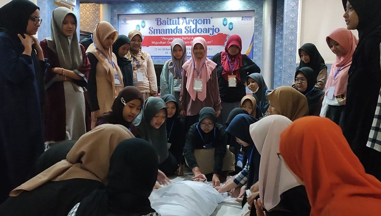 Siswi putri kelas 11 SMAMDA Sidoarjo sedang belajar mengkafani jenazah dipandu guru instruktur.( Foto : Jatimkini.com/ Rere Nia )