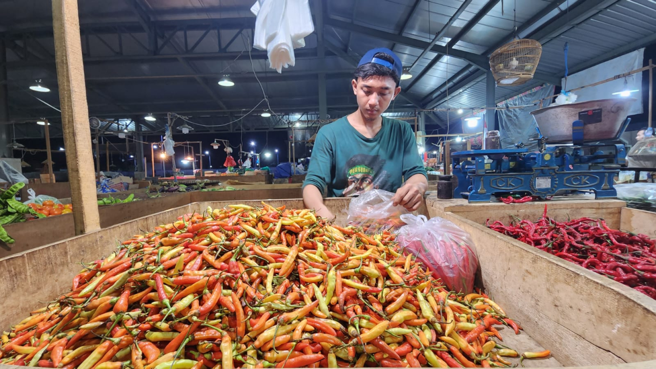 Seorang pegadang cabai rawit di Pasar Induk Sidotopo Surabaya sedang melayani pembeli. Foto : Peni Widarti