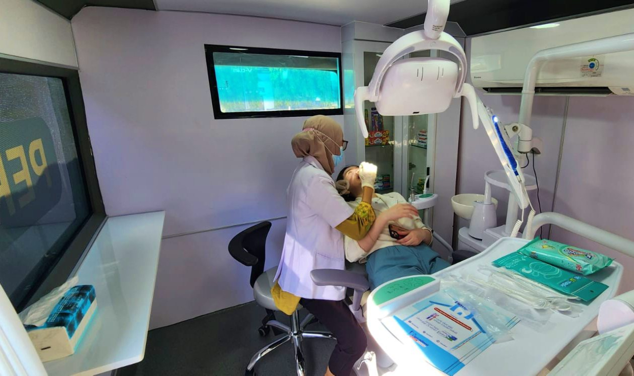 Dokter gigi di bus periksa gigi keliling sedang memberikan layanan pemeriksaan gigi kepada pasien. Foto : Peni Widarti