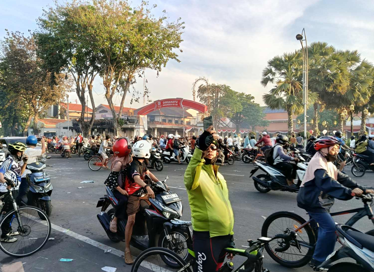 Warga Surabaya yang berolahraga pada Minggu (31/8/3025) pagi berswafoto di depan Grahadi yang dibakar dalam aksi unjuk rasa di Surabaya. (Foto: Rochman Arief/jatimkini.com)