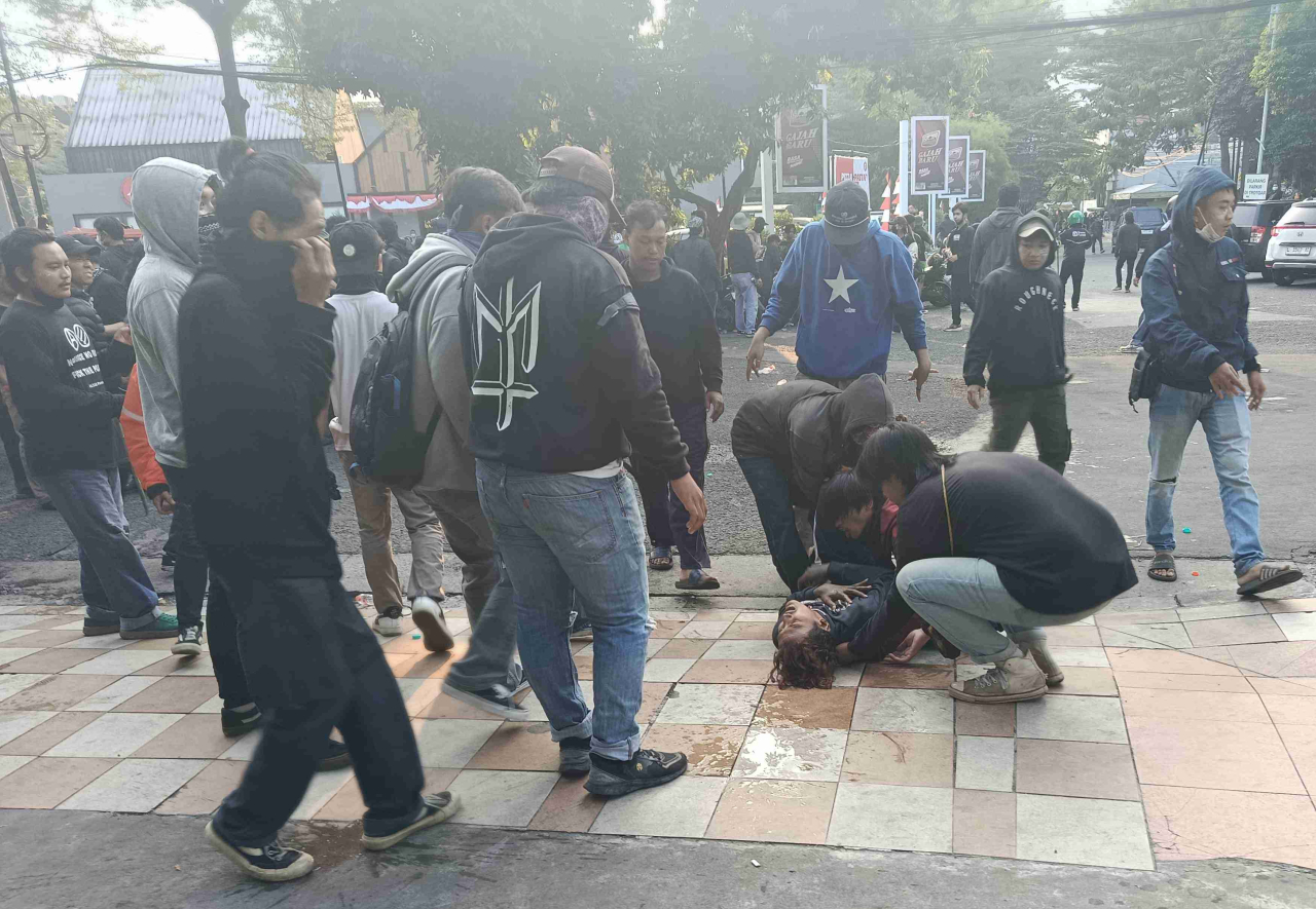 Sejumlah demonstran memberi pertolongan kepada rekannya yang terdampak gas air mata di depan Hotel Kampi. (Foto: Rochman Arief/jatimkini.com)
