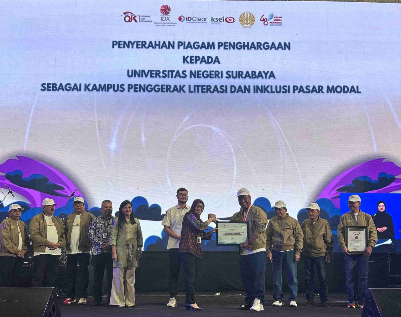 Kepala OJK Jatim, Yunita Lida Sari didampingi menyerahkan penghargaan kepada Rektor Unesa, Prof.,Dr., Nurhasan atas upayanya memperkenalkan pasar modal di kampus. (foto: dok.BEI)