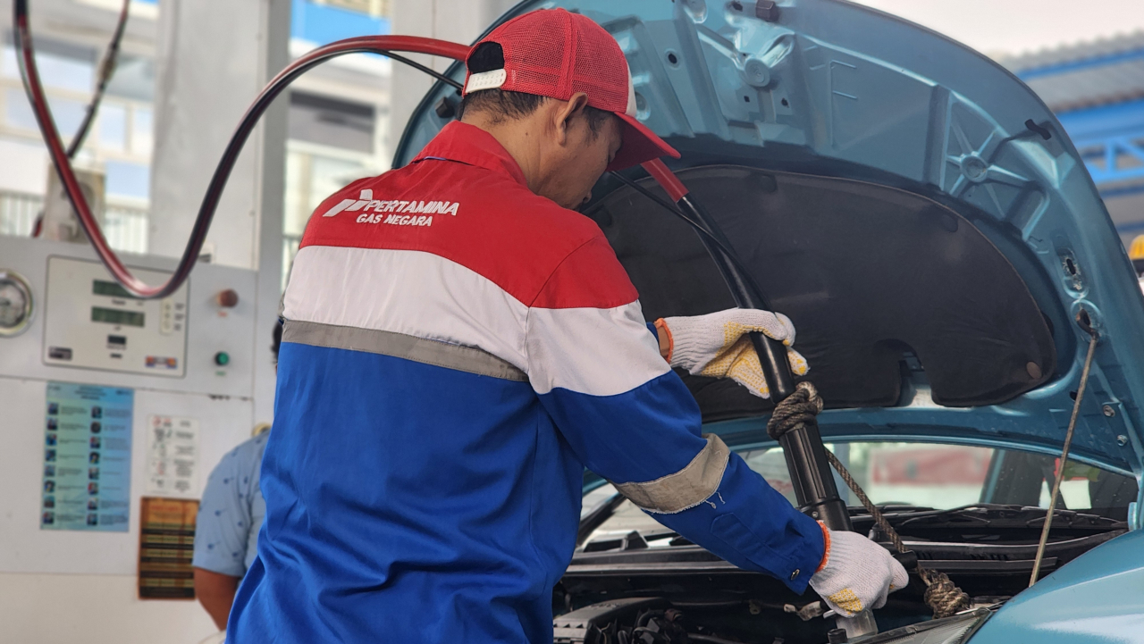 Petugas SPBG Ngagel sedang melakukan proses pemasangan pipa pengisian Gasku pada knop tangki gas taksi Blue Bird pada Kamis (18/9/2025). Foto : Peni Widarti