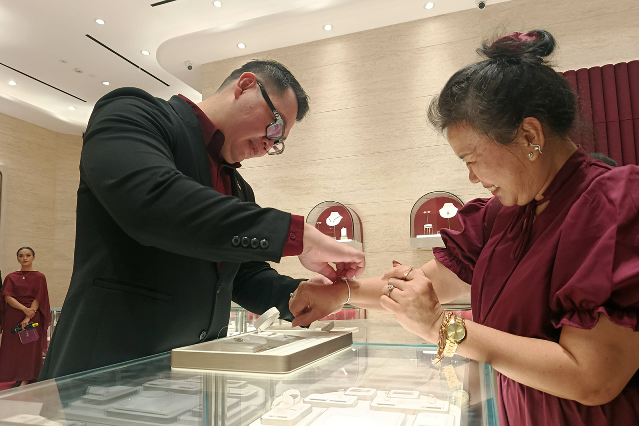 General Manager Frank & co., Rolly Soesanto (kiri) membantu memasangkan perhiasan kepada customer loyalti di sela reopening di Pakuwon Mall. (foto: Rochman Arief/jatimkini.com)