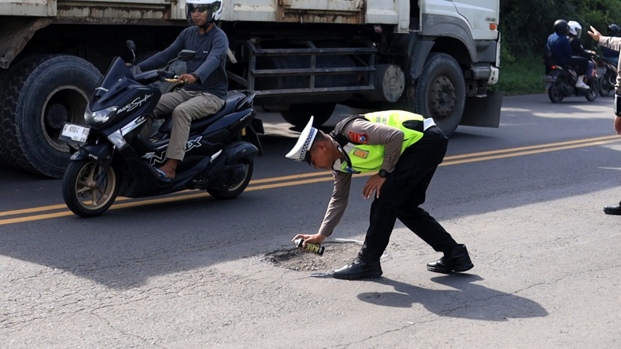 Petugas Satlantas mengambil langkah tepat menandai jalan rusak untuk mengantisipasi kecelakaan ( Foto : Humas Polda Jatim )